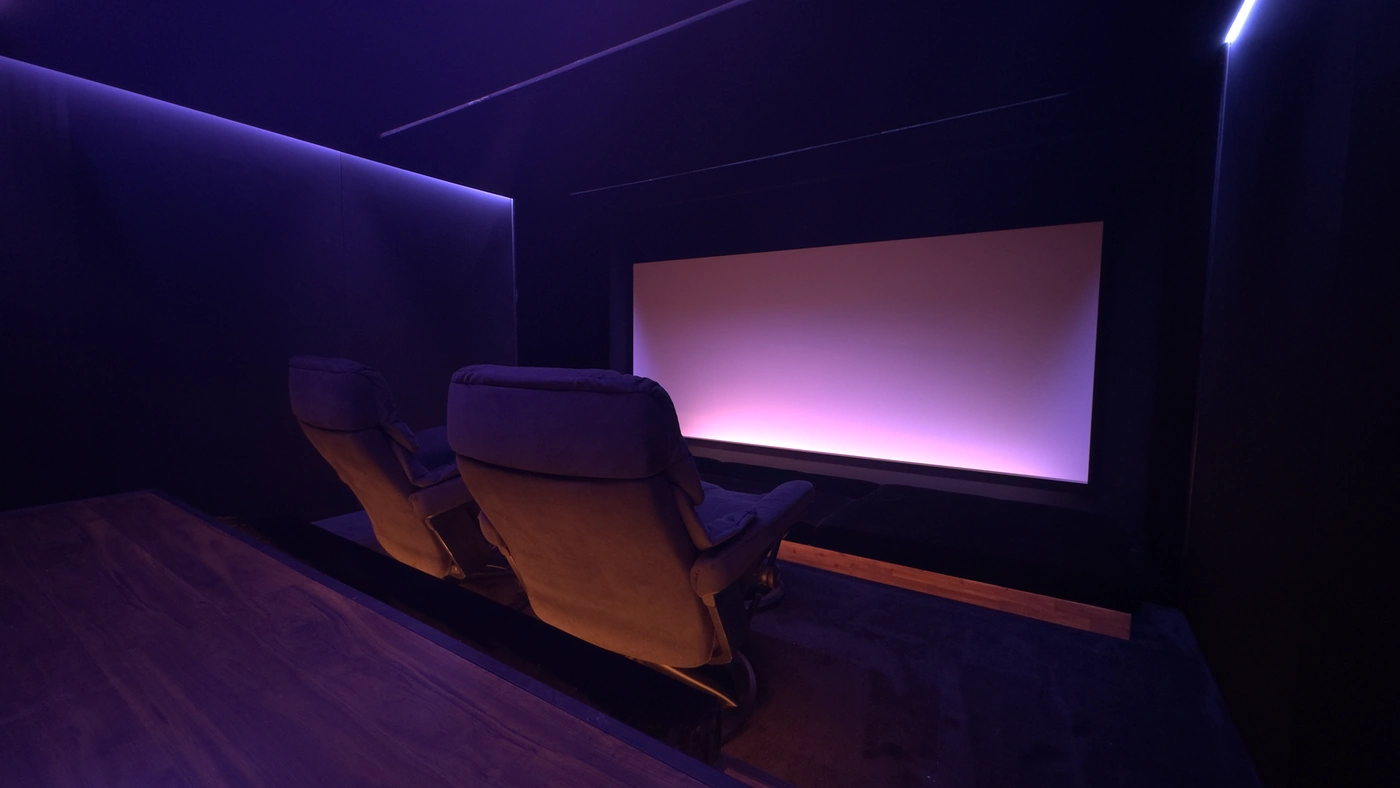 Seitlicher Blick auf die vorderen Lounge-Sessel und die 21:9-Leinwand