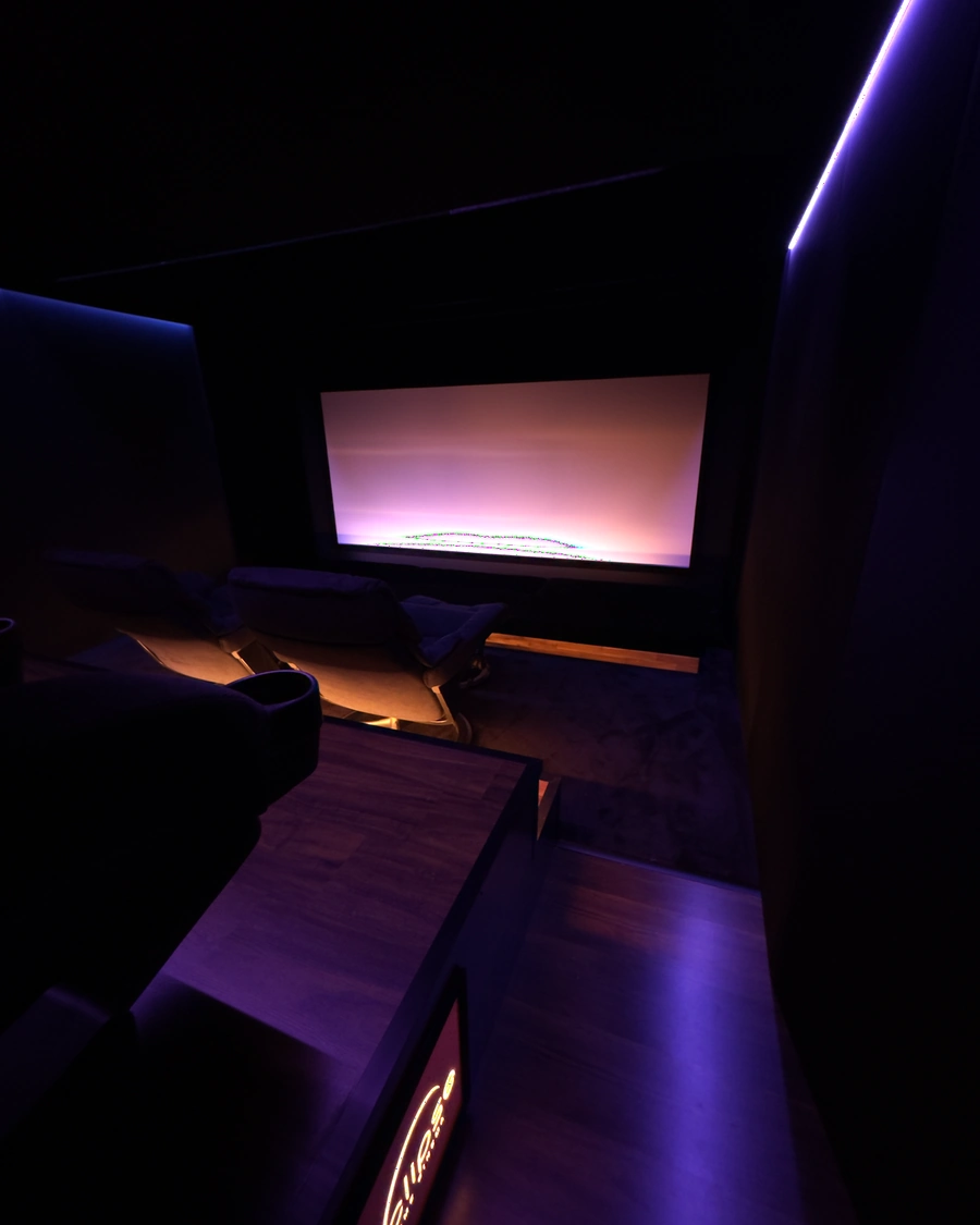 Seitlicher Blick ueber Lounge-Sessel auf eine magenta beleuchtete Leinwand