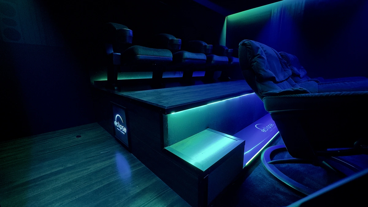 Seitlicher Blick auf Podest, Lounge-Sessel und blau-gruene Stufenbeleuchtung