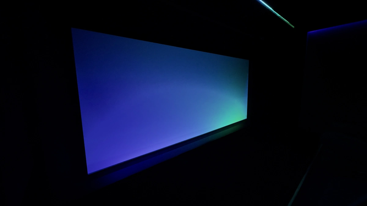Cinemascope-Leinwand mit blau-cyanfarbener Lichtstimmung im dunklen Kinoraum